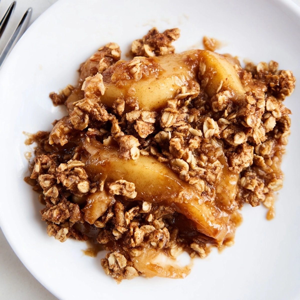 A slice of homemade Cinnamon Caramel Pear Crumble showcases the juicy pear filling inside.