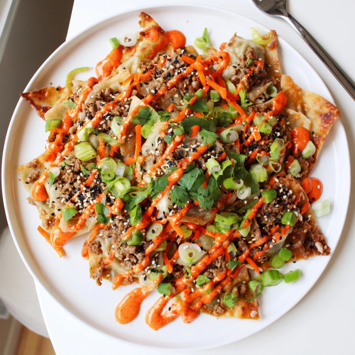 Crispy wonton chips covered in flavorful gyoza filling creating Japanese Gyoza Nachos.