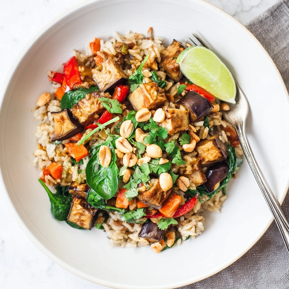 Creamy Thai Peanut Eggplant Rice Bake topped with fresh cilantro and lime wedges.