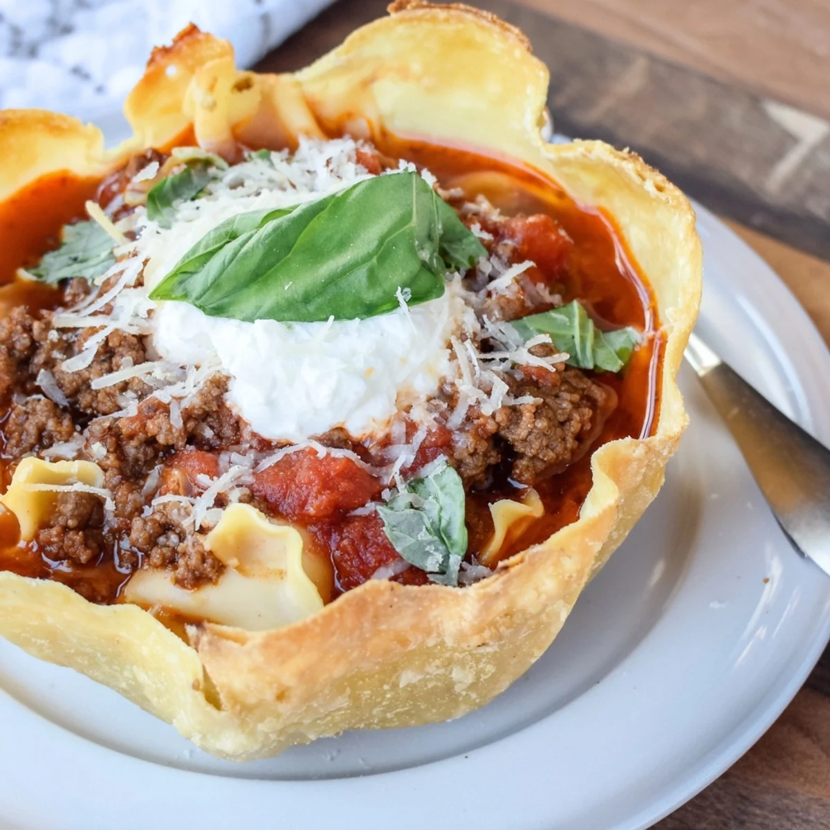 Crispy pizza crust bowls filled with savory lasagne soup, topped with ricotta.