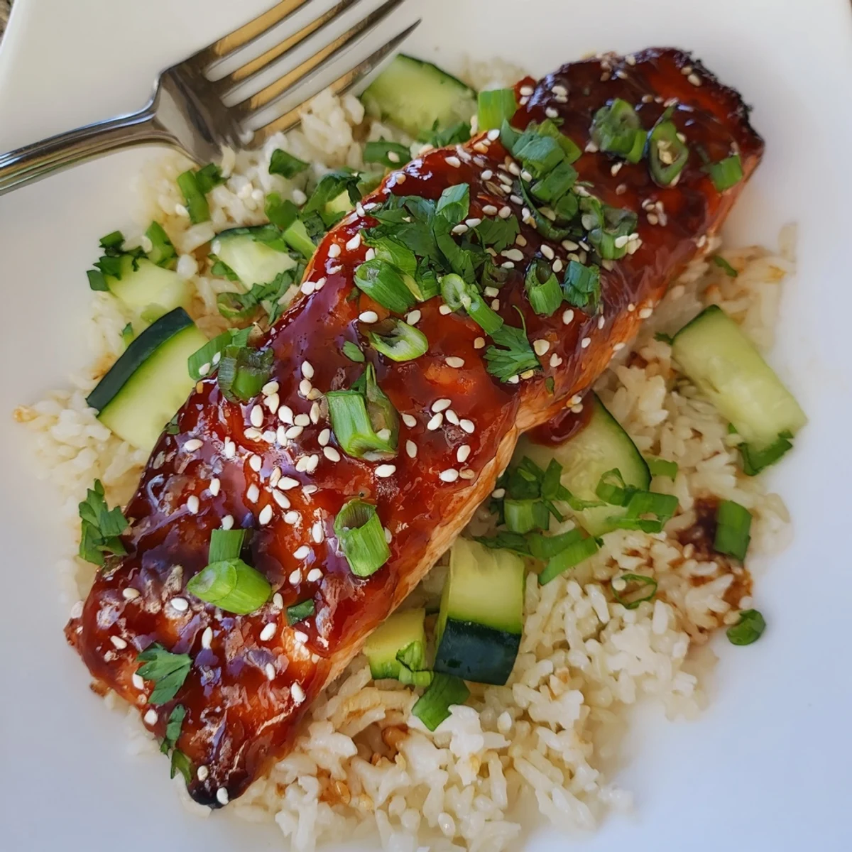 Sriracha glazed salmon garnished with fresh herbs on aromatic cucumber rice.  