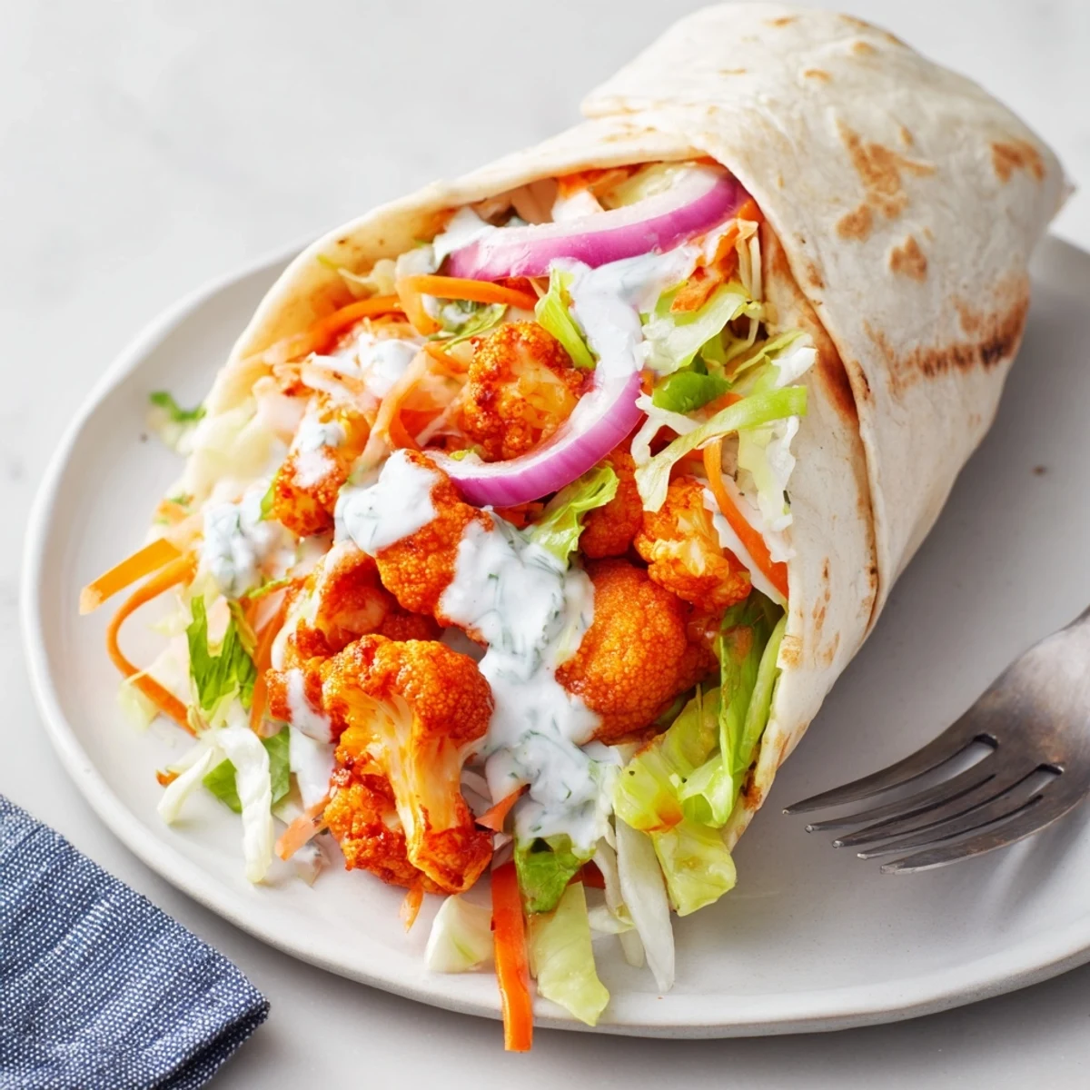 Spicy buffalo cauliflower florets nestled in soft tortillas with zesty blue cheese sauce.  