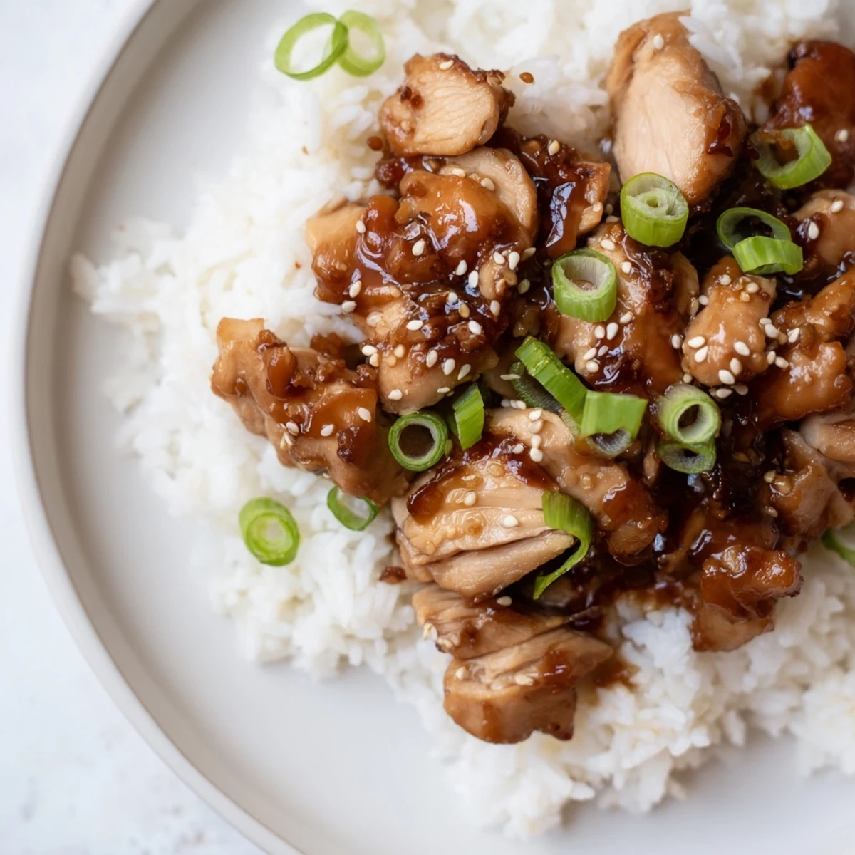 A hearty bowl of slow cooker teriyaki chicken with rice, garnished with green onions and sesame seeds.