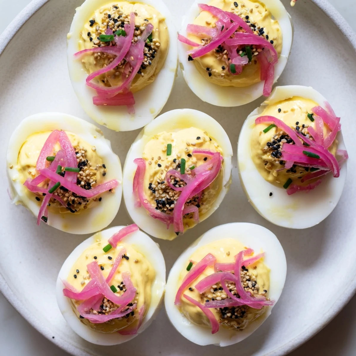 Everything-Spiced Deviled Eggs topped with pickled shallots, ready to serve as a delicious appetizer.