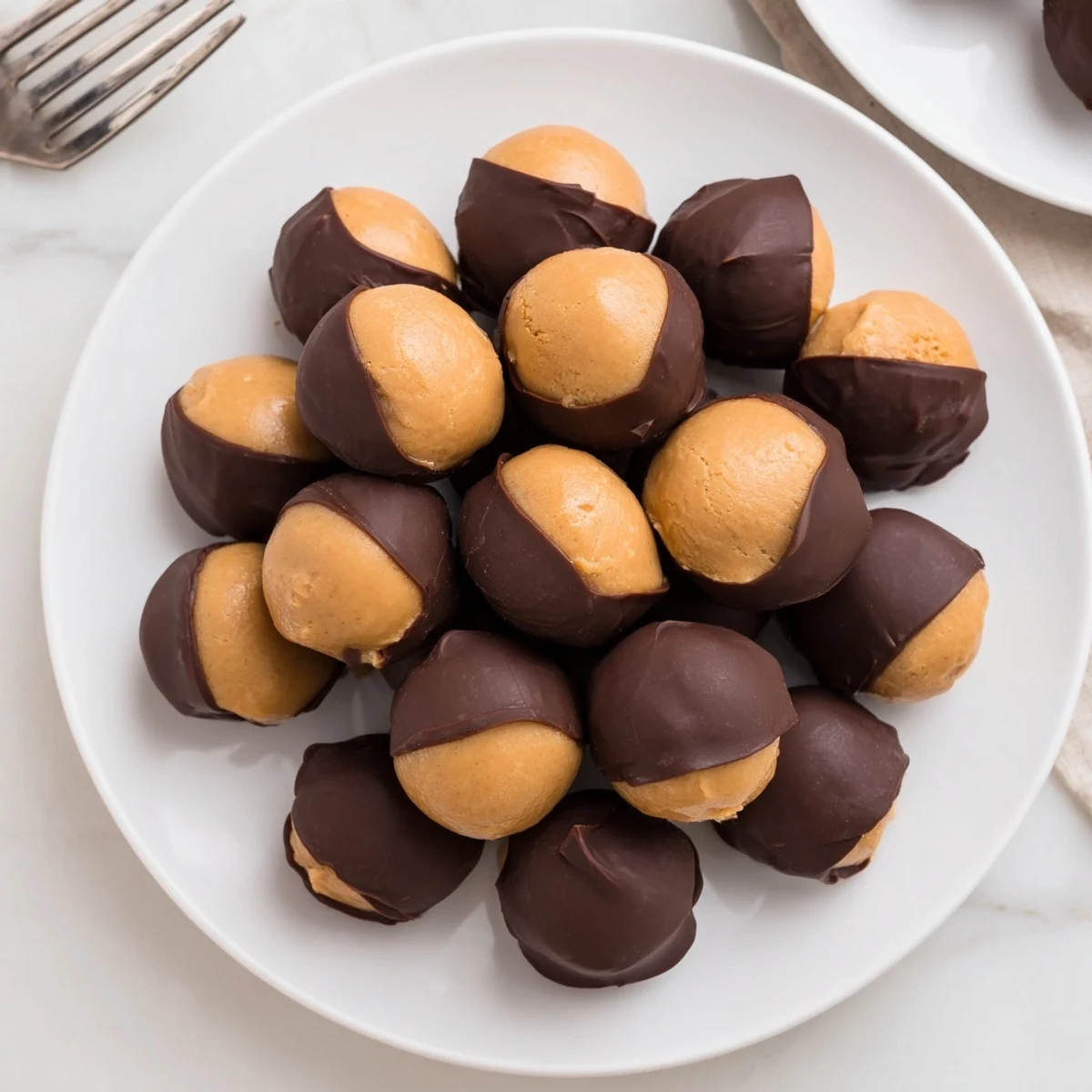 Perfectly round Peanut Butter Buckeyes, partially dipped in glossy chocolate, a holiday treat.