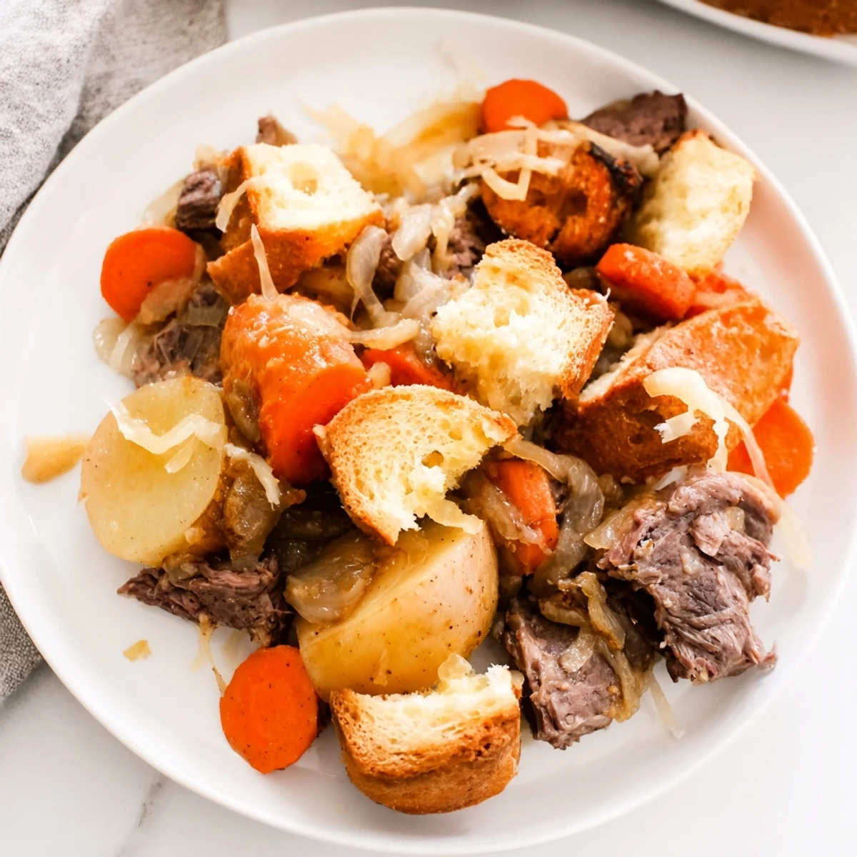 A steaming dish of French Onion Pot Roast Casserole featuring crispy bread and flavorful onions.