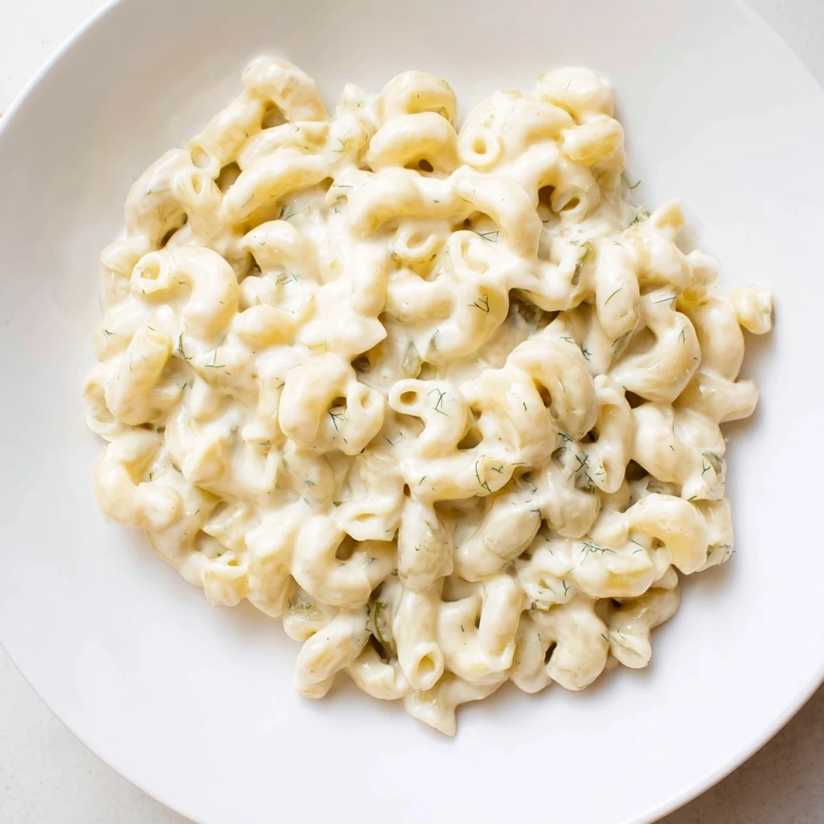 A tempting close-up of Pickle Mac and Cheese, creamy with a sprinkle of fresh dill.