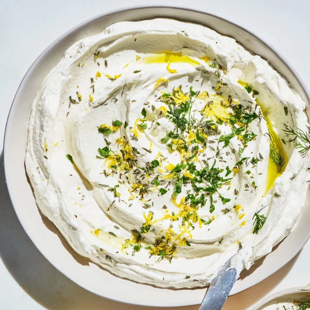 Smooth, creamy Whipped Feta with Greek Seasoning, ready to be scooped up with crunchy pita chips.