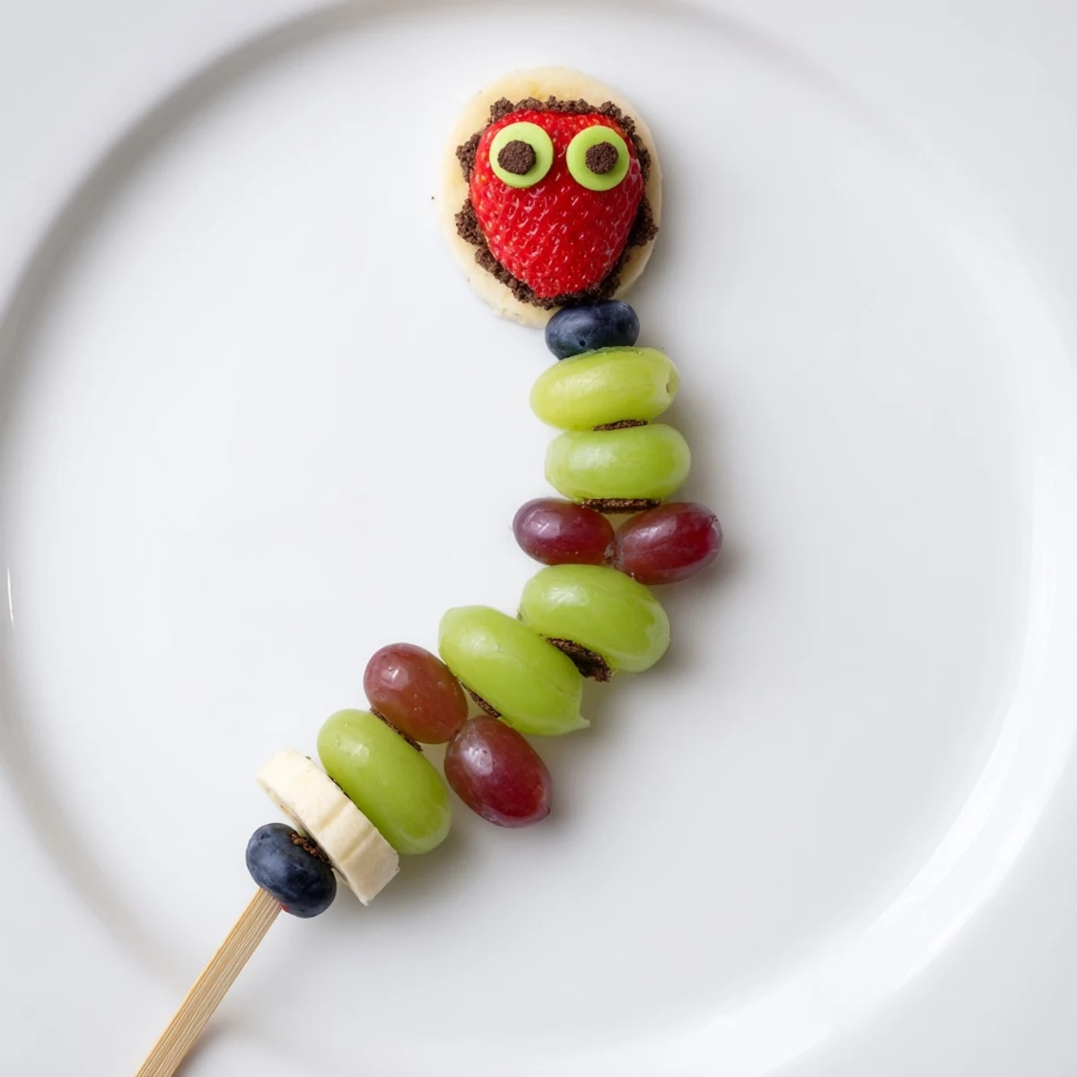 Vibrant Caterpillar Fruit Skewers on a crunchy cookie crumb track, a colorful kid-friendly snack.