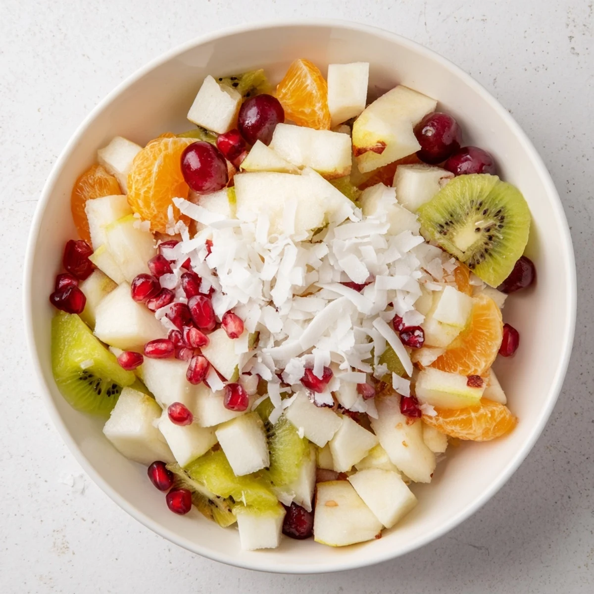 Bright red pomegranate seeds highlight this Snowflake Fruit Medley, a refreshing winter salad with citrus dressing.