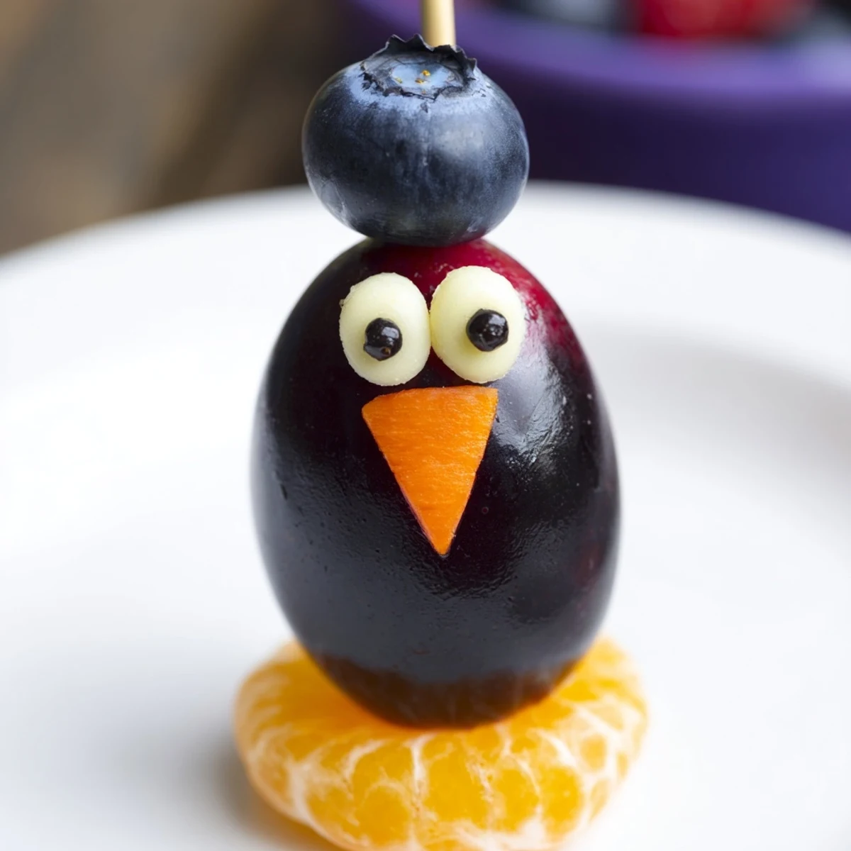 Plate of whimsical Penguin Fruit Skewer Army featuring colorful fruit and chocolate chip eyes.