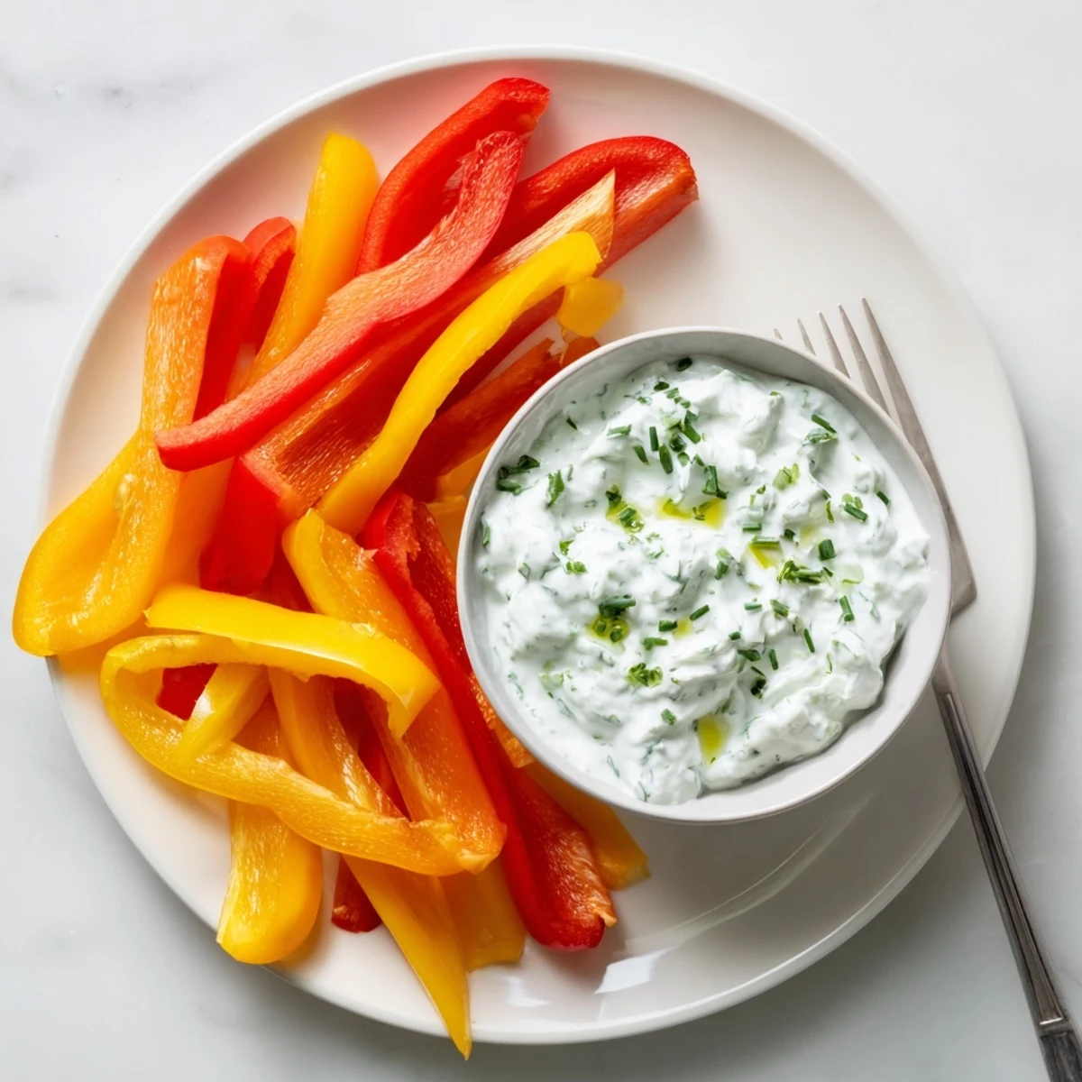 Colorful platter of bell pepper strips with a cool, creamy Greek yogurt dip in the center.