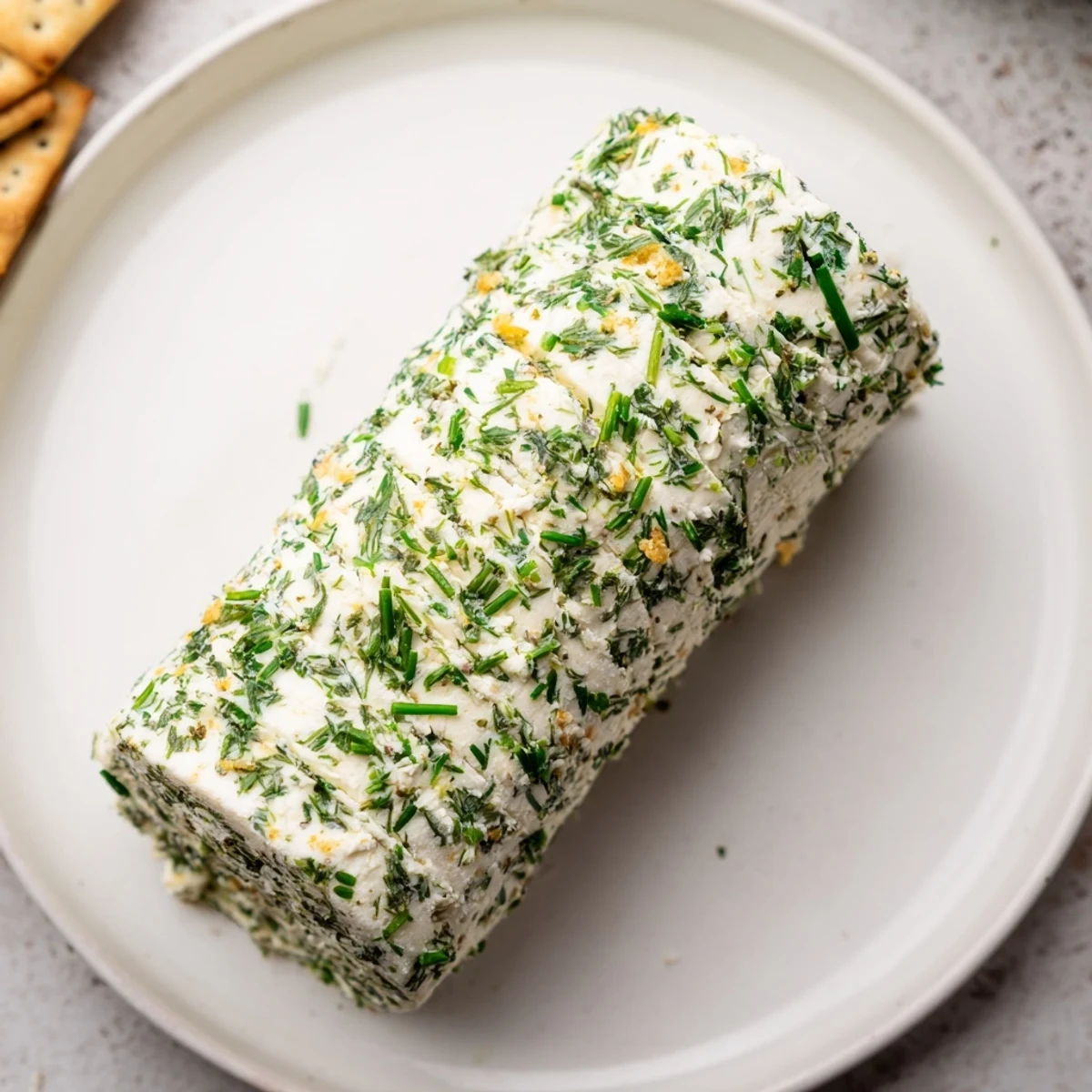 A close-up of Herb-Coated Cheese Log, its creamy texture visible, perfect for sharing and dipping.