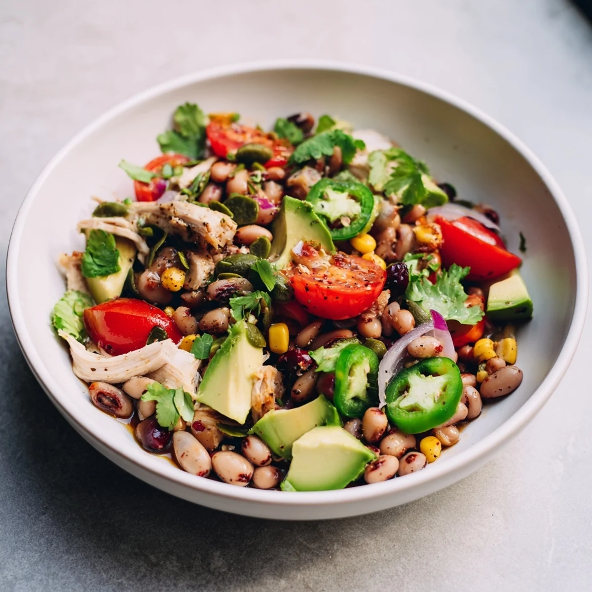 Dense Southwestern Bean Salad bursting with vibrant colors, served with fresh cilantro and lime wedges.