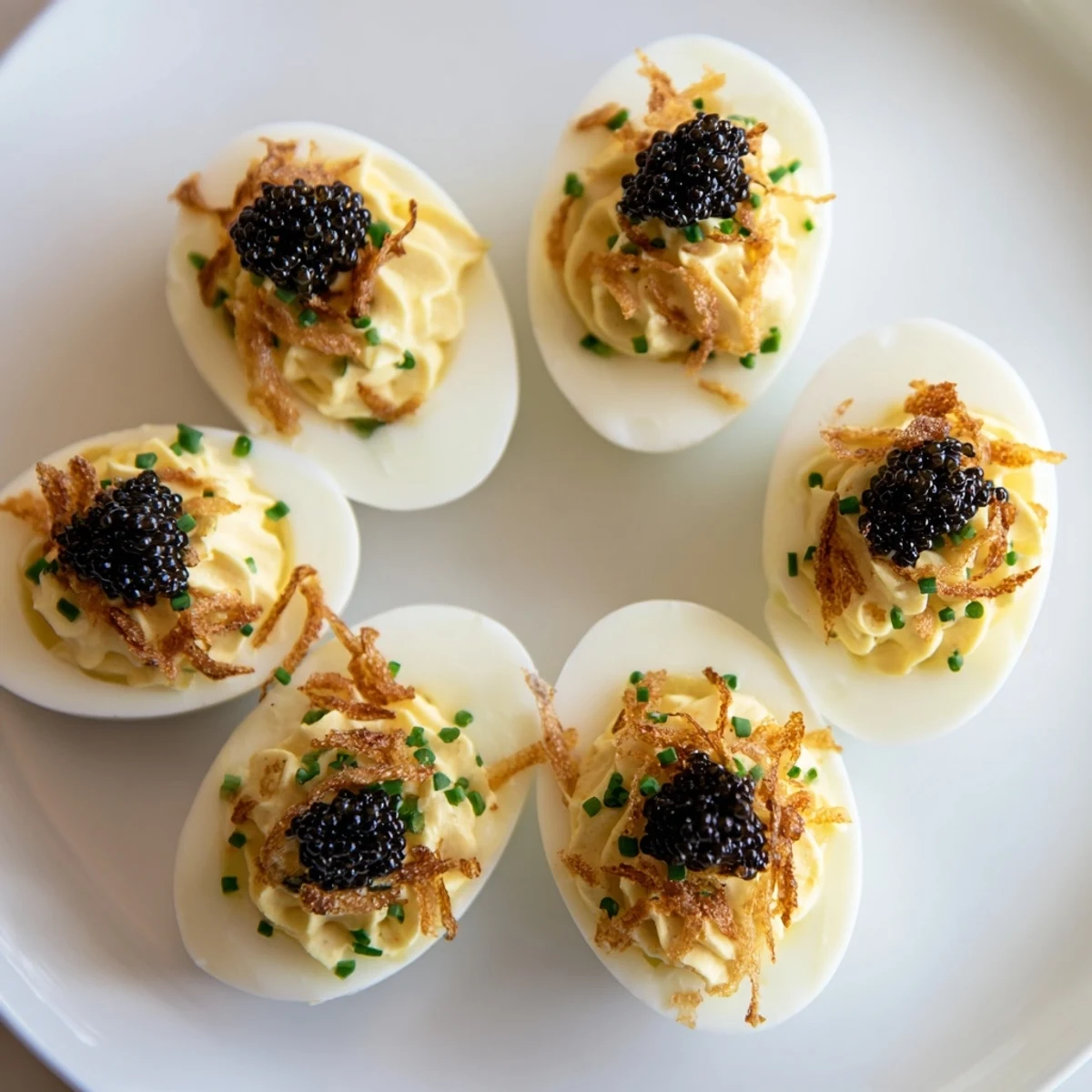 Elegant deviled eggs topped with glistening caviar and crunchy shallots, a gourmet appetizer.