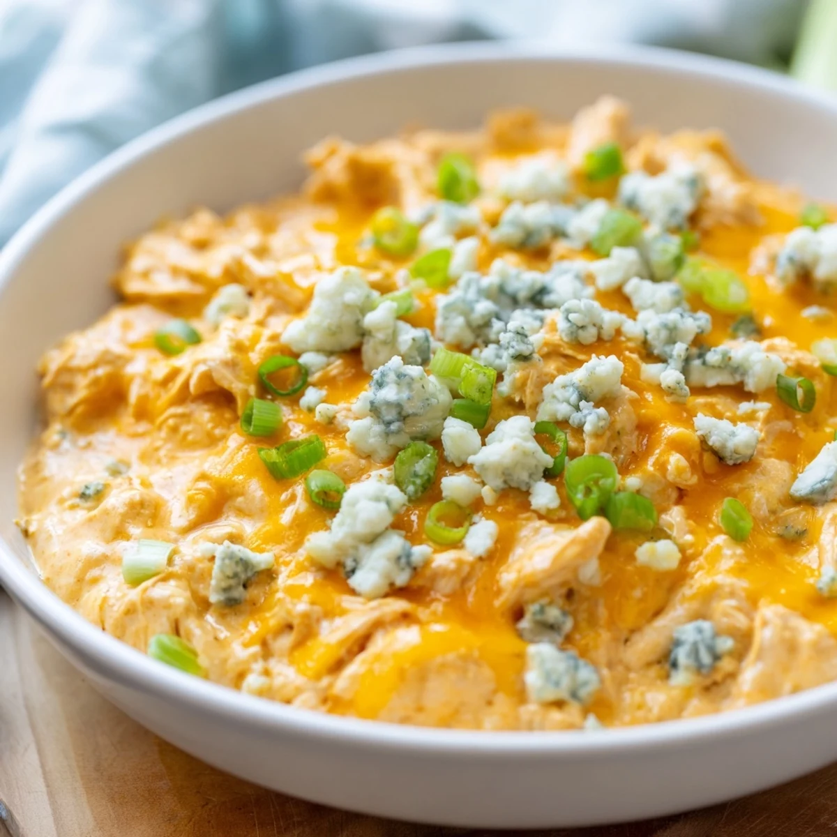 A warm and creamy bowl of Buffalo Chicken Dip, topped with melted cheddar and fresh green onions, perfect for dipping with tortilla chips.  