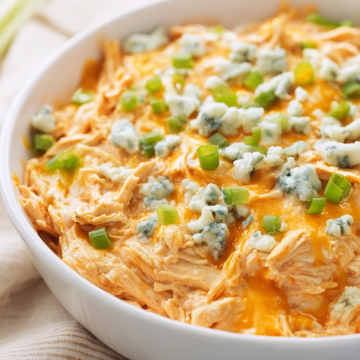 Spicy and cheesy Buffalo Chicken Dip garnished with scallions, ready to be scooped up with sturdy crackers or crusty bread.