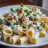 Steaming plate of Creamy Lemon Feta Chicken Pasta garnished with fresh parsley and lemon zest.