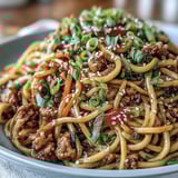 Ground turkey and chewy noodles coated in glossy sweet-spicy Korean sauce, garnished with sesame seeds.