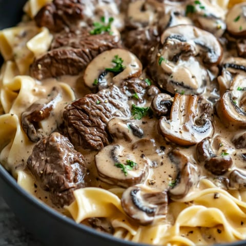 A bowl of beef stroganoff with mushrooms and noodles.