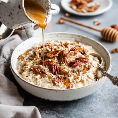 A bowl of oatmeal with maple syrup and pecans.