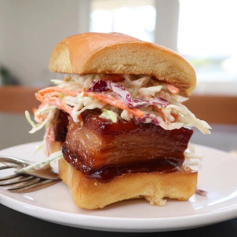 Succulent bourbon glazed pork belly sliders piled high with creamy slaw on toasted buns.  
