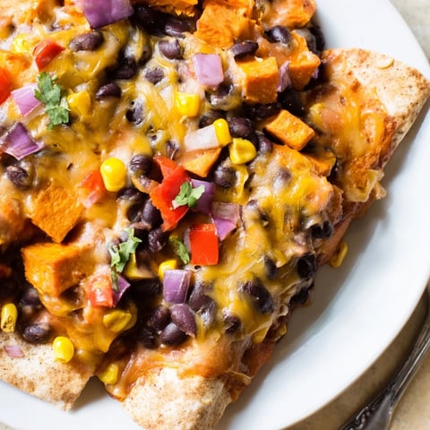 Aromatic Spicy Black Bean & Sweet Potato Enchiladas topped with melted cheese and fresh cilantro.  