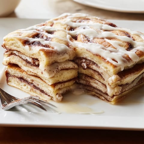 Decadent cinnamon roll pancake bake drizzled with creamy glaze, perfect for brunch.  