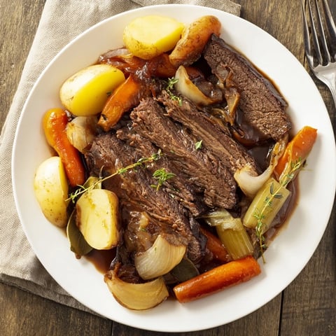 Tender beer-braised brisket with colorful root vegetables dish ready to serve.  