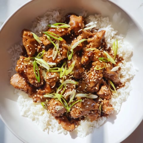 Easy slow cooker teriyaki chicken glistening with sauce, served over a bed of fluffy white rice.