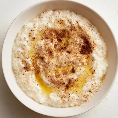 Steaming bowl of rice pudding with leftover rice, swirled with cinnamon, perfect for dessert.