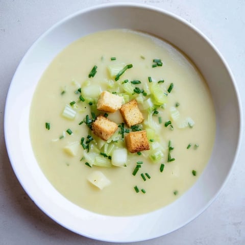 Steaming bowl of Potato Leek Soup, perfectly smooth and garnished with fresh green chives.