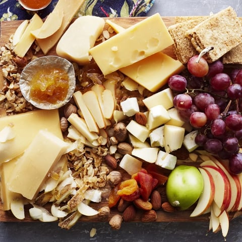 A lavish Cornucopia Harvest Board overflowing with colorful fruits, cheeses, meats, and festive garnishes for guests.