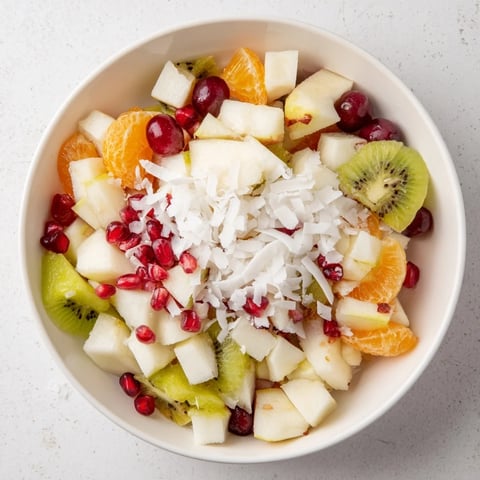 Bright red pomegranate seeds highlight this Snowflake Fruit Medley, a refreshing winter salad with citrus dressing.