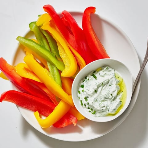 Vibrant red, yellow, and green bell pepper strips surrounding the creamy Greek yogurt dip.