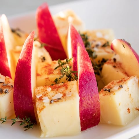 Smoked paprika-dusted cheeses and apple wedges create the vibrant visual appeal of The Autumn Ember appetizer.