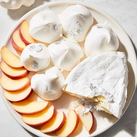 Elegant Pearly Gates cheese board features creamy brie, crisp meringue, and juicy white peaches, ready to enjoy.