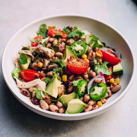 Dense Southwestern Bean Salad bursting with vibrant colors, served with fresh cilantro and lime wedges.