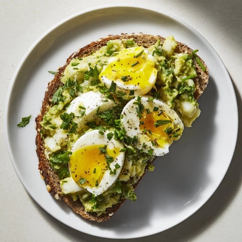 Creamy Avocado Egg Smash on toasted bread, garnished with fresh herbs and ready to enjoy.