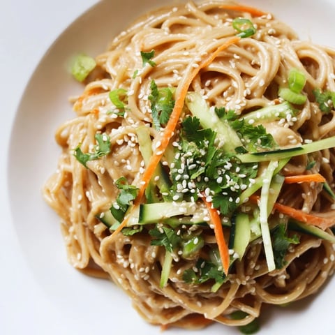 Silky cold sesame noodles tossed with crisp vegetables and a rich, creamy sauce, ready to eat.