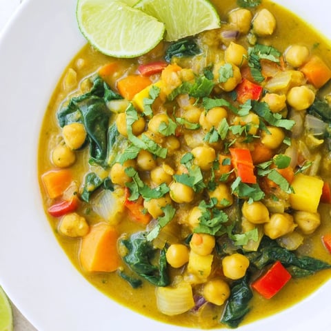A steaming bowl of creamy Chickpea Curry, garnished with fresh cilantro and a lime wedge.