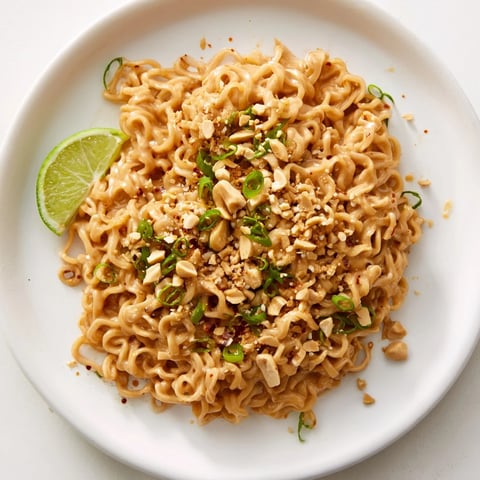 Steaming bowl of Instant Peanut Thai Sauce Noodles garnished with fresh cilantro and chopped peanuts.
