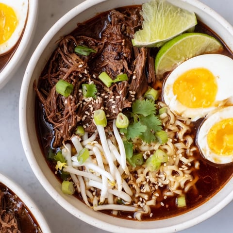 Steaming bowl of Chaos Cooking Birria Ramen, with tender beef, ramen, and vibrant toppings.