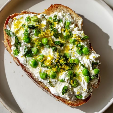Bright green pea & mint ricotta toast on golden sourdough, perfect light brunch.