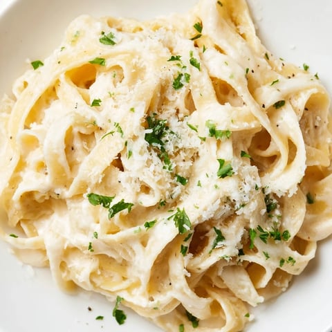Creamy Easy Creamy Cauliflower Alfredo pasta twirled on a fork, garnished with fresh parsley and extra Parmesan.
