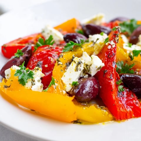 Roasted Greek Salad with caramelized Mediterranean vegetables, olives, and creamy feta on a platter.