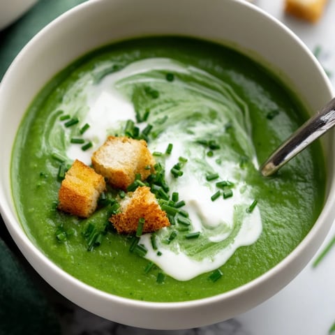 Cream of Broccoli Soup in a rustic bowl, garnished with fresh chives and croutons, steaming warmly.