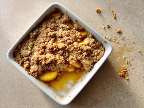 A white bowl of food with a peach on top.