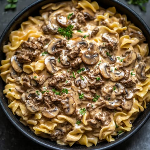 A bowl of beef stroganoff with mushrooms and noodles.