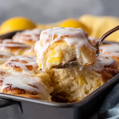 A fork is stuck in a lemon sweet roll.